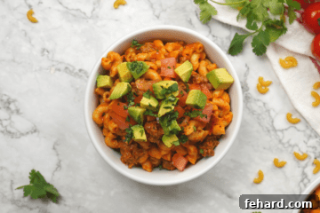 Top down view of taco pasta topped with avocado, cilantro, and tomato.