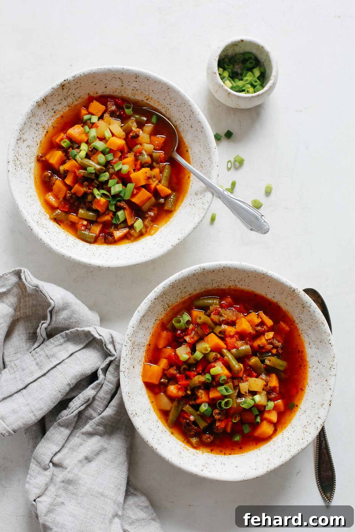A close-up of the finished ground beef vegetable soup recipe, garnished with vibrant green herbs.