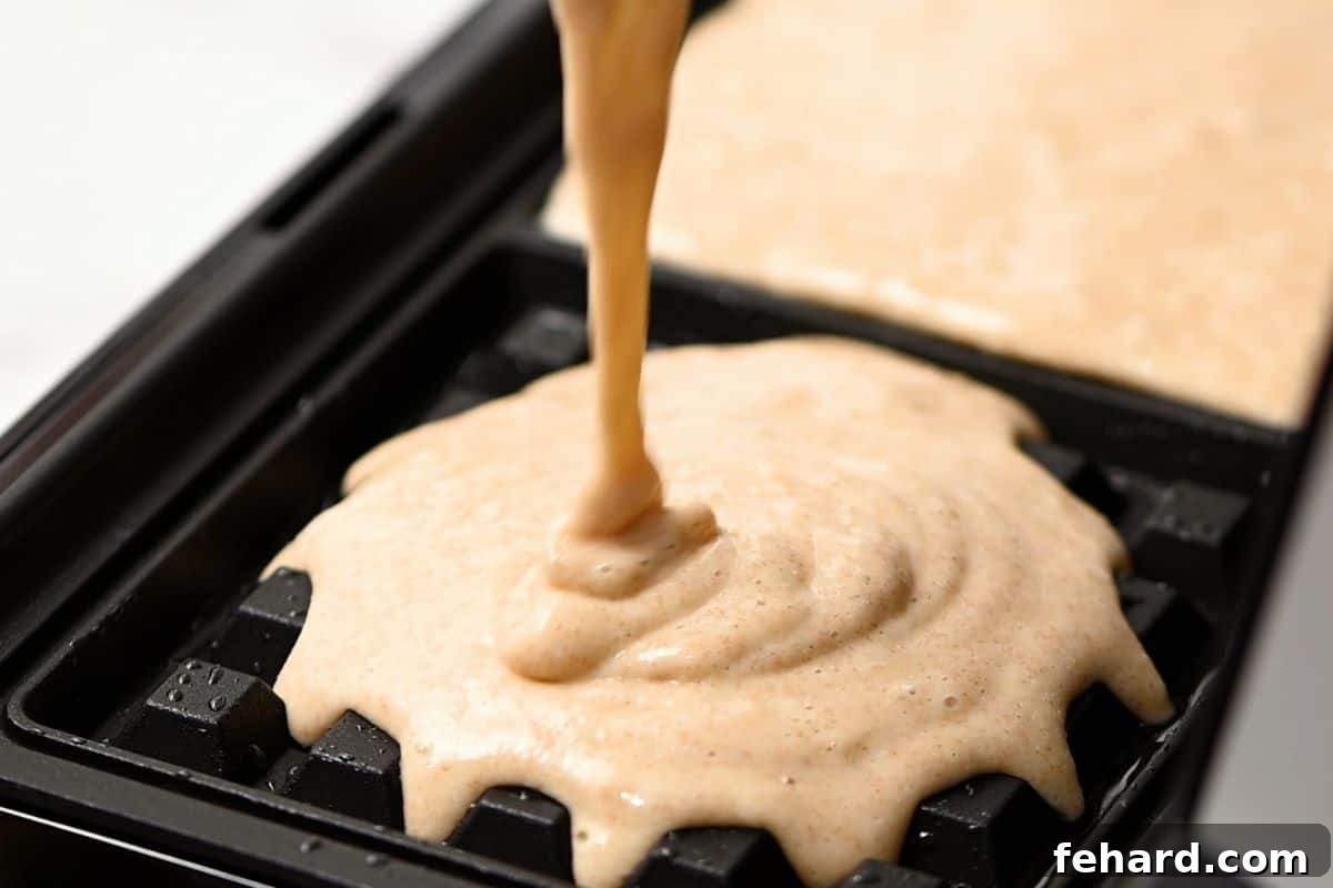 Cooking Waffles with Whole Wheat Flour A cook carefully ladling whole wheat waffle batter onto a preheated waffle iron, ensuring even distribution.