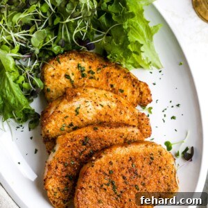 Air fryer pork chops on a white plate with a side salad.