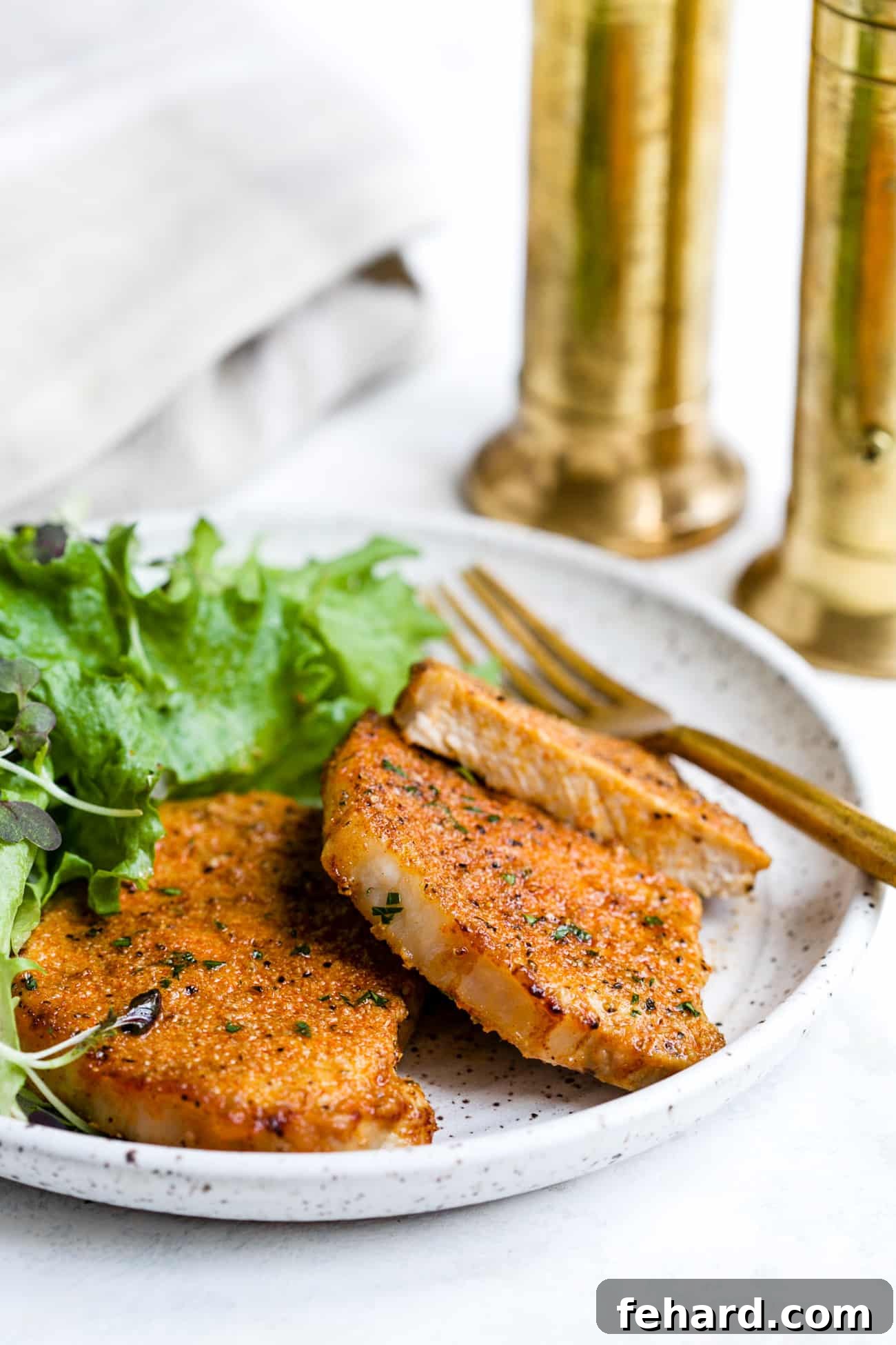 Golden Crispy Air Fryer Pork Chops 6 Succulent air fryer pork chops served on a white plate alongside a vibrant green side salad.