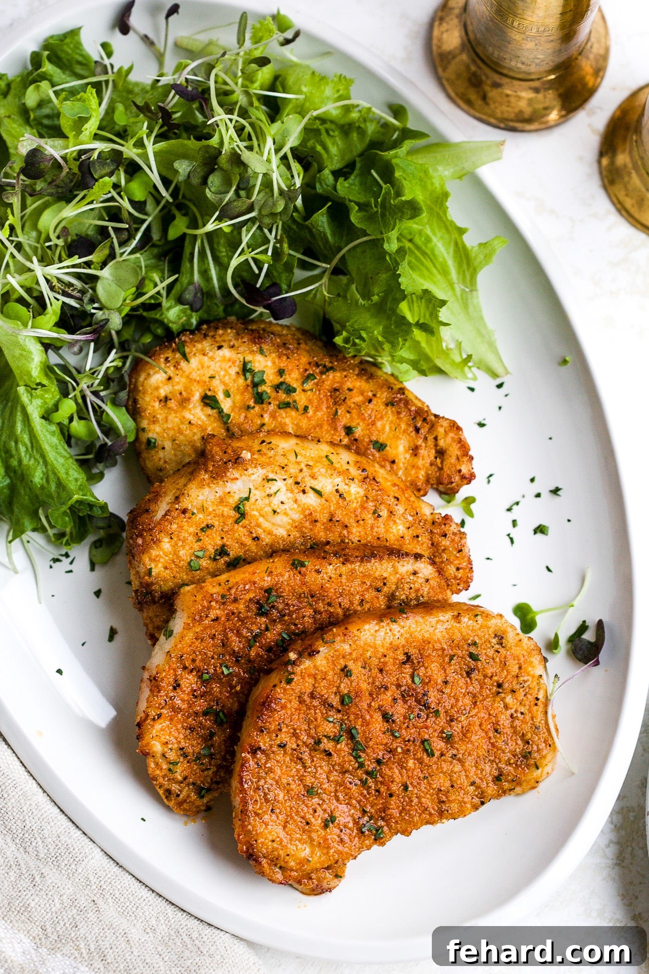 Golden Crispy Air Fryer Pork Chops 7 Air fryer pork chops presented beautifully on a white plate, served alongside a fresh green salad.