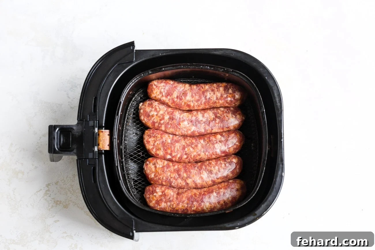 Uncooked sausage in air fryer basket.