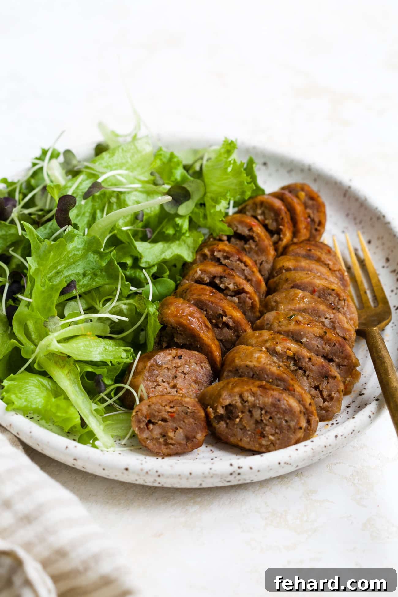 Sliced and plated air fryer sausage with a side salad. 