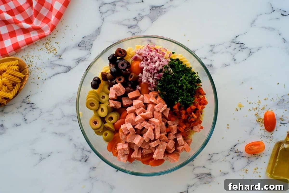 Homemade Pasta Salad with Salami Pasta with all the toppings for antipasto pasta salad in glass bowl.