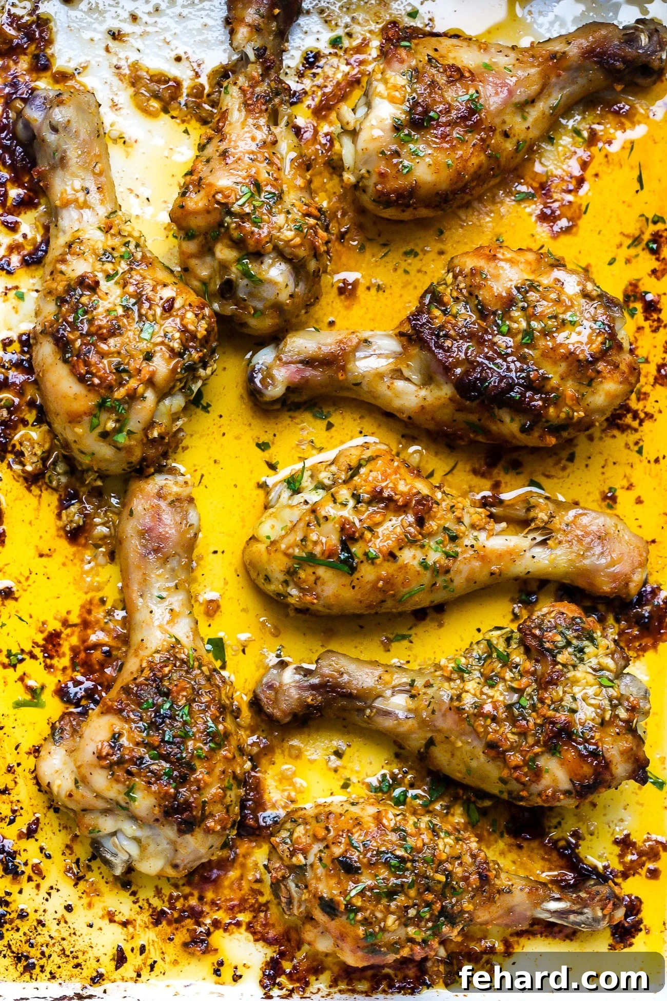 Irresistible Garlic Butter Chicken Legs 7 Close up of garlic butter baked chicken drumsticks in a white baking dish.
