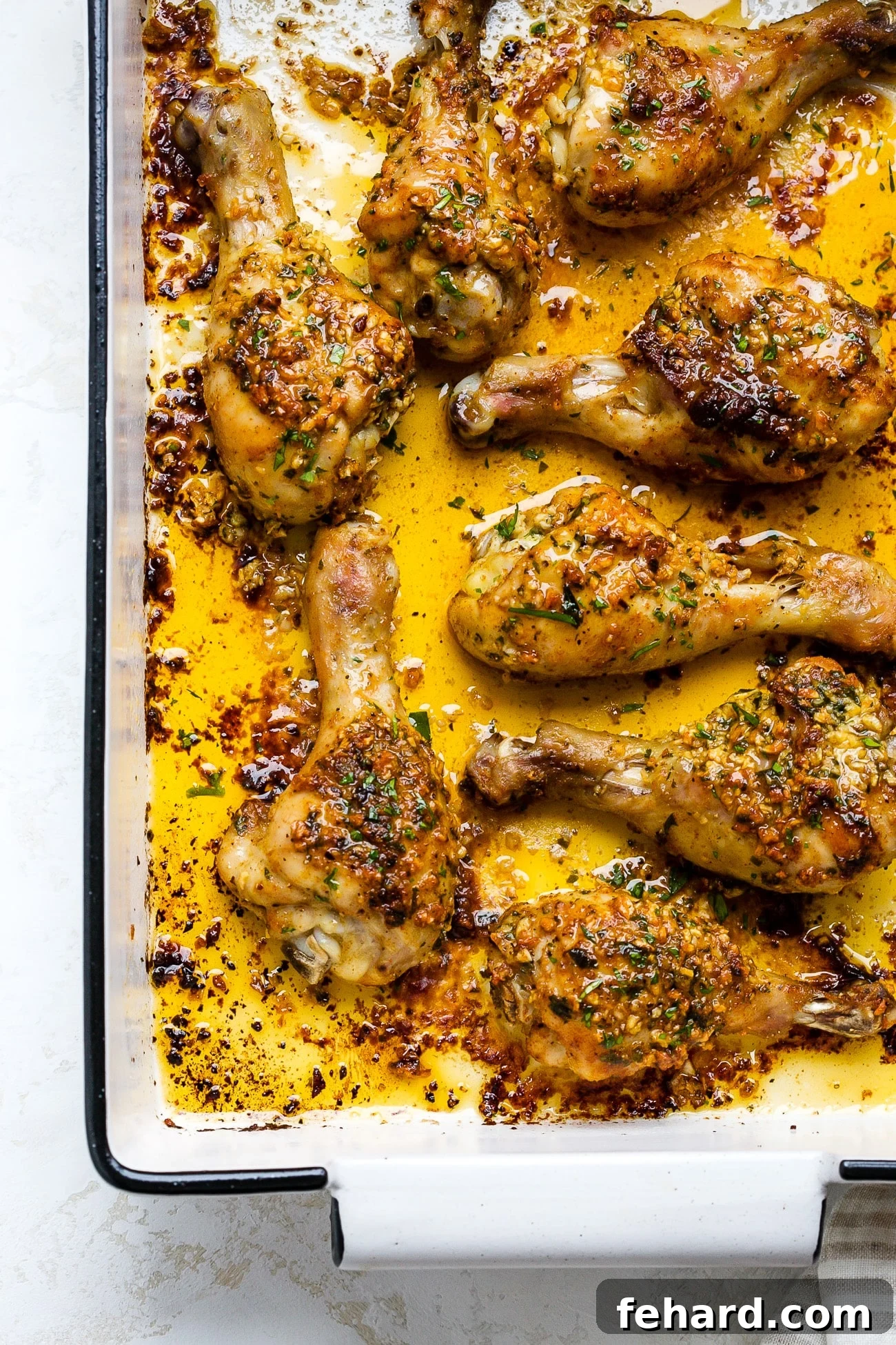 Irresistible Garlic Butter Chicken Legs 8 Garlic butter baked chicken drumsticks in a white baking dish.