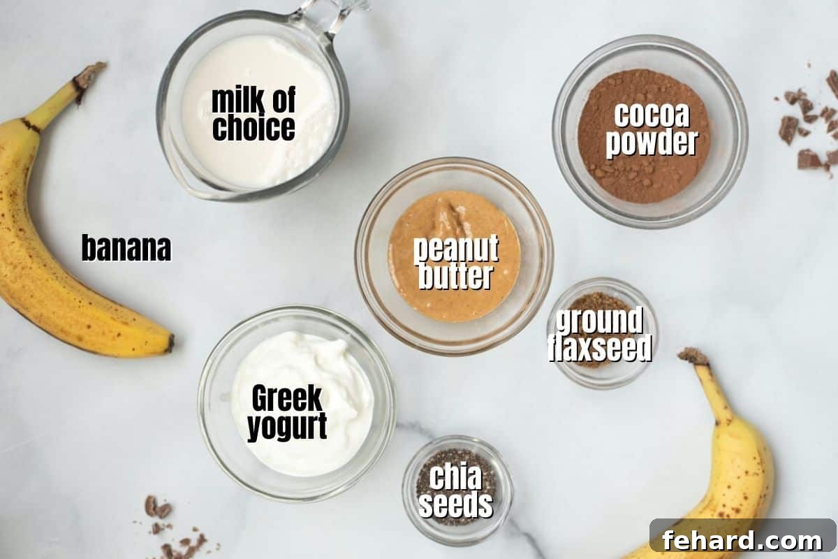 Carefully arranged ingredients for a delicious peanut butter chocolate smoothie, including a bottle of milk, a container of Greek yogurt, a jar of natural peanut butter, a ripe banana, chia seeds, ground flaxseed, and cocoa powder, all neatly labeled on a kitchen counter.