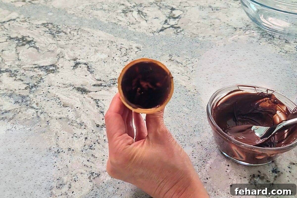 Lining Ice Cream Cones with Chocolate Sugar cone being lined with melted chocolate inside.