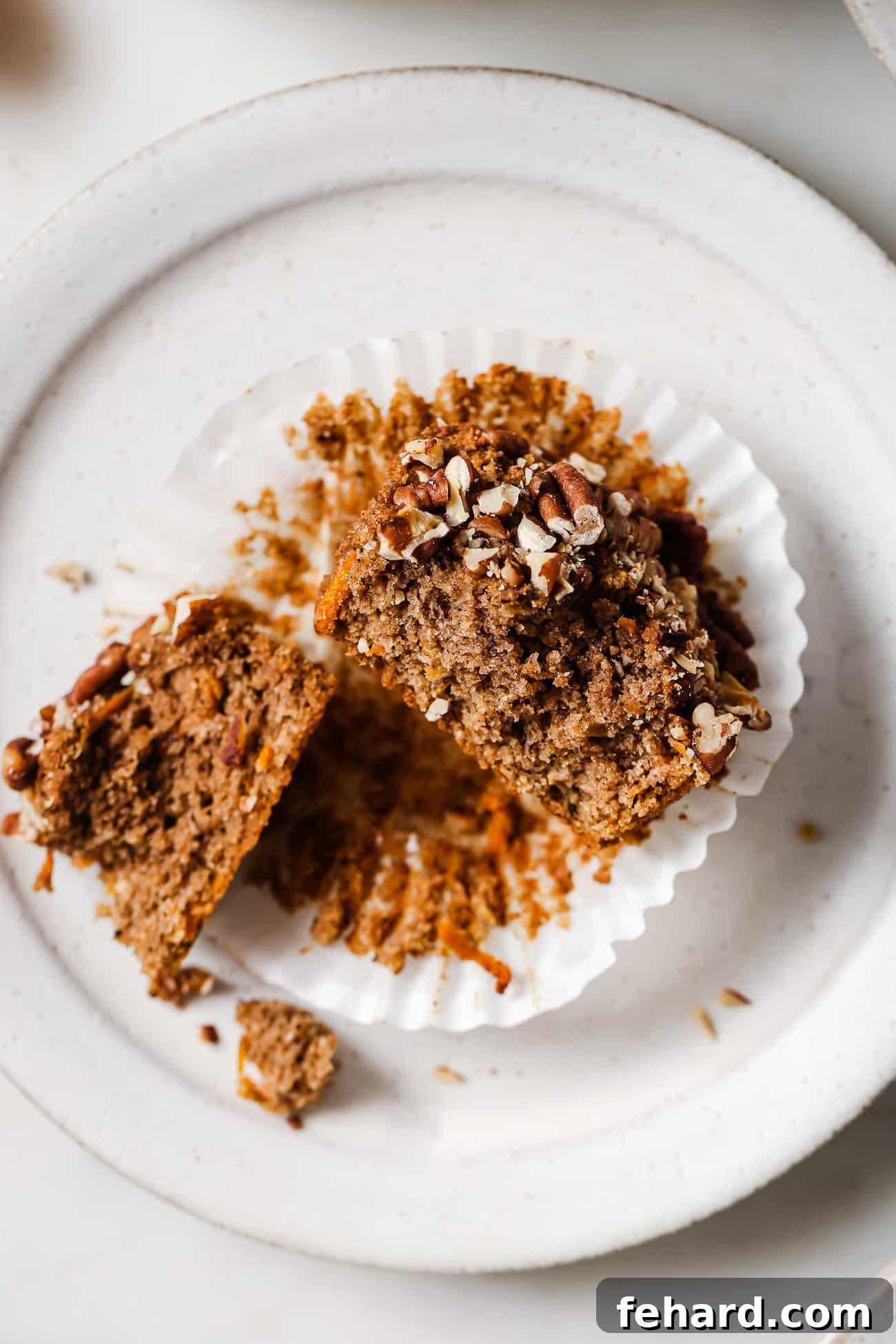 Wholesome Gluten-Free Carrot Muffins 6 A freshly baked gluten-free carrot muffin perfectly sliced in half on a white plate, revealing its fluffy texture and carrot pieces.