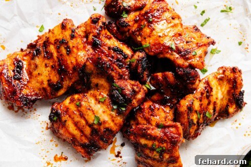 Grilled chicken thighs resting on parchment paper on a countertop