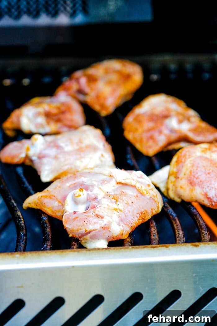 Raw seasoned chicken thighs placed directly on hot grill grates