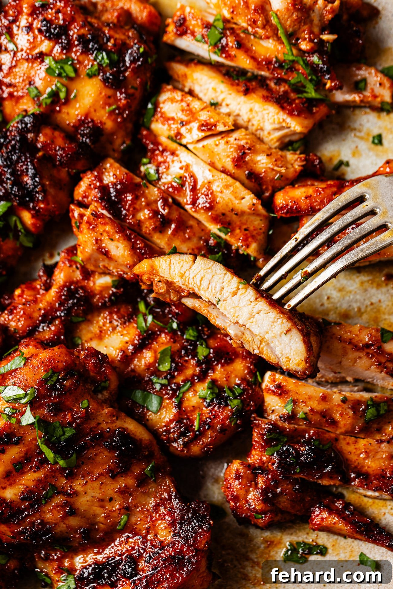 Close-up of a fork holding a succulent slice of grilled chicken, showing its tenderness