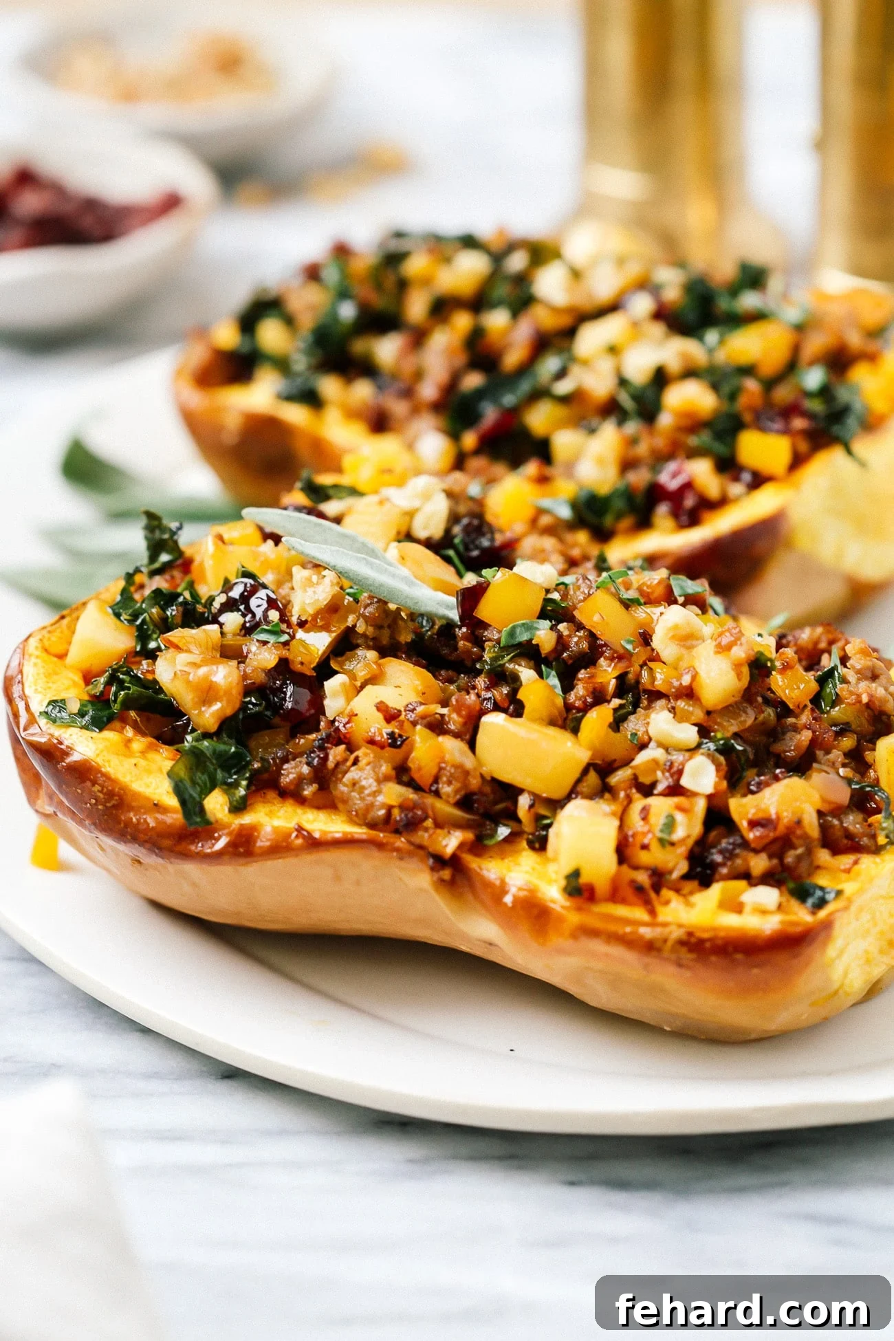 Two fully stuffed butternut squash halves, bursting with savory filling, beautifully arranged on a white serving plate, garnished with fresh herbs.