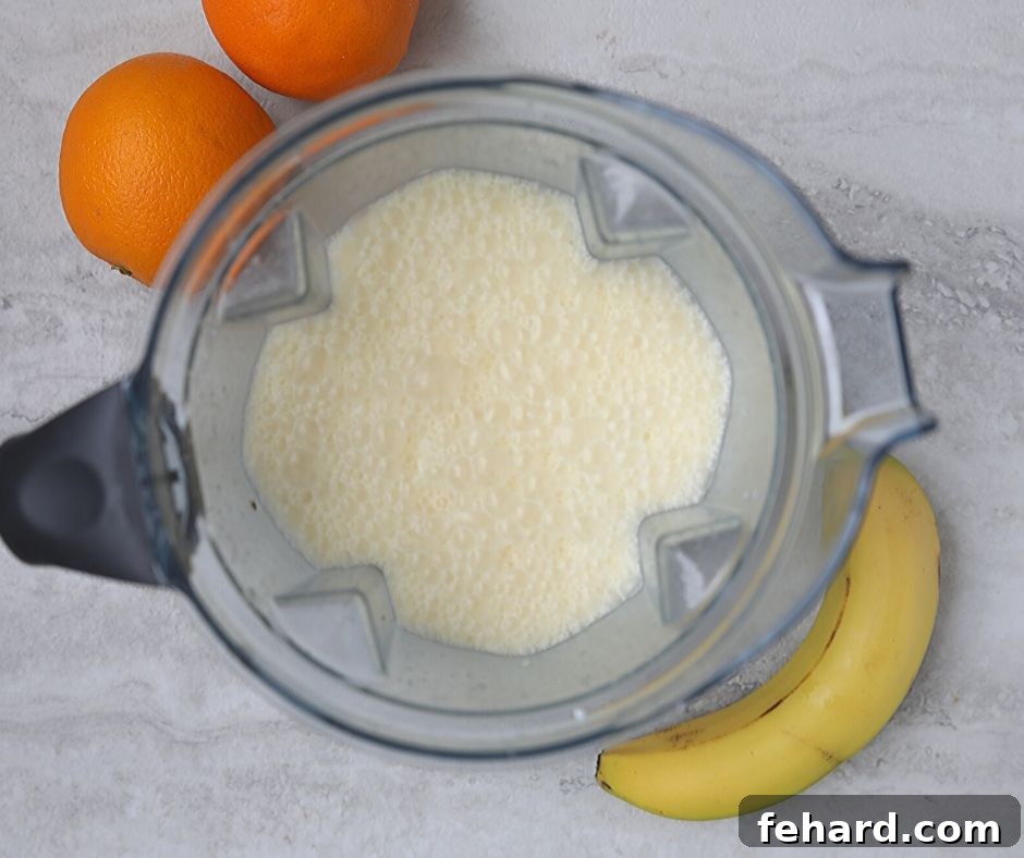 Pina Colada Smoothie ingredients blending to a creamy consistency in a high-speed blender.