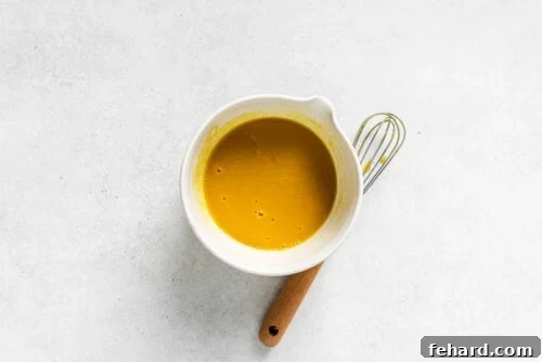 Dijon sauce inside of a white bowl, freshly whisked.