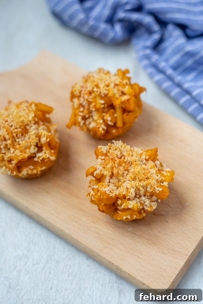 Golden brown Mac and Cheese Muffins on a rustic wooden cutting board, ready to be enjoyed.
