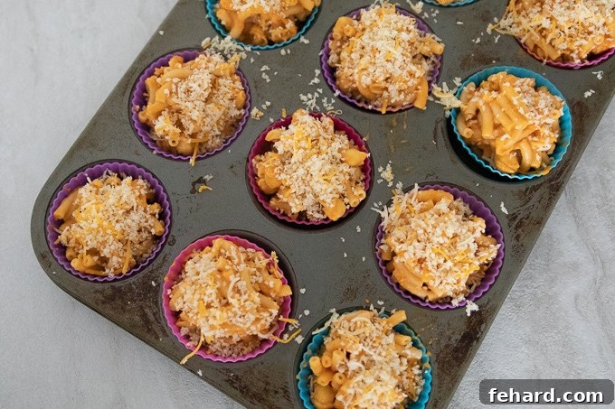 A baking tray filled with freshly baked Mac and Cheese Muffins, topped with a golden breadcrumb crust.