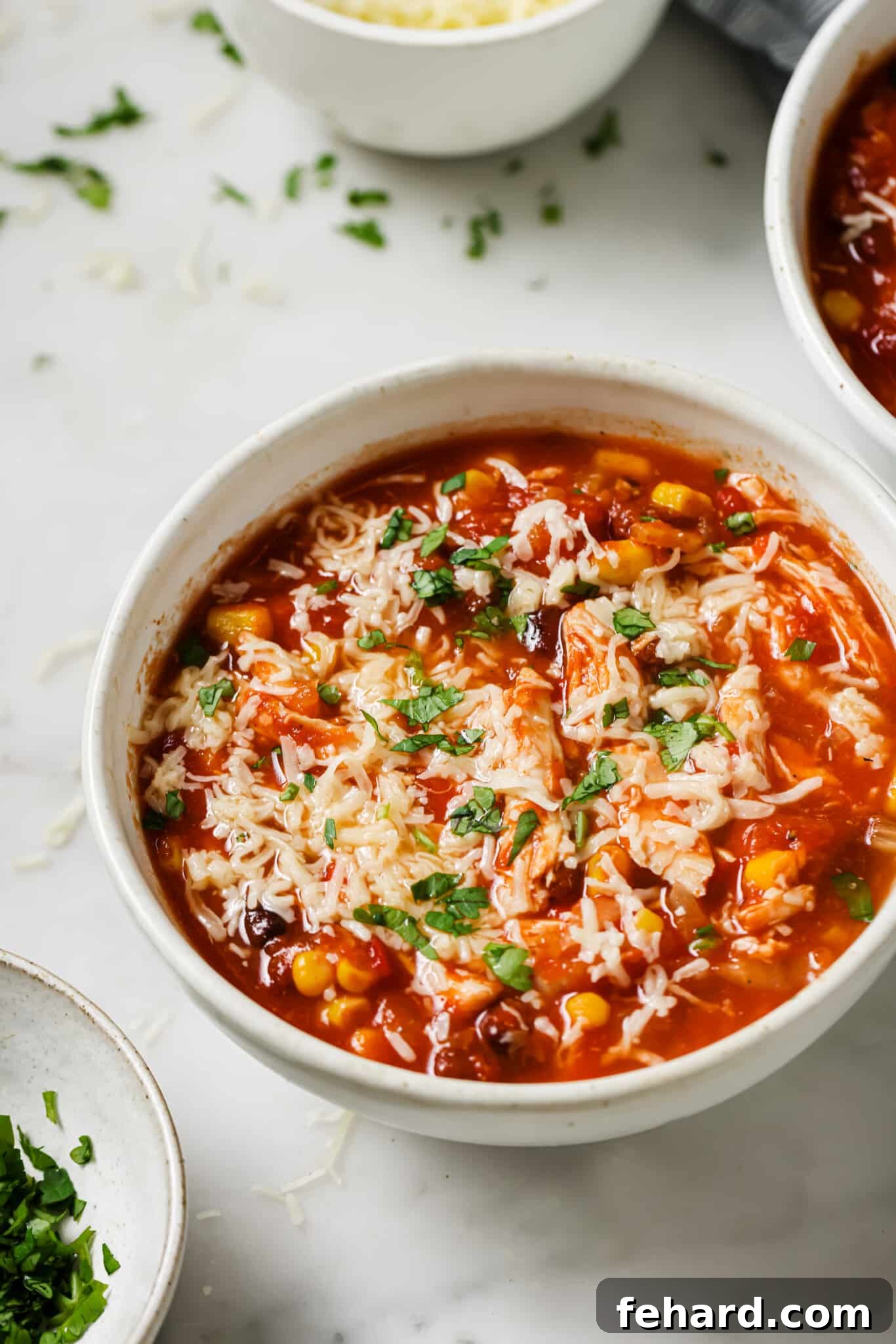 Close up of slow cooker chicken chili topped with cilantro and cheese.