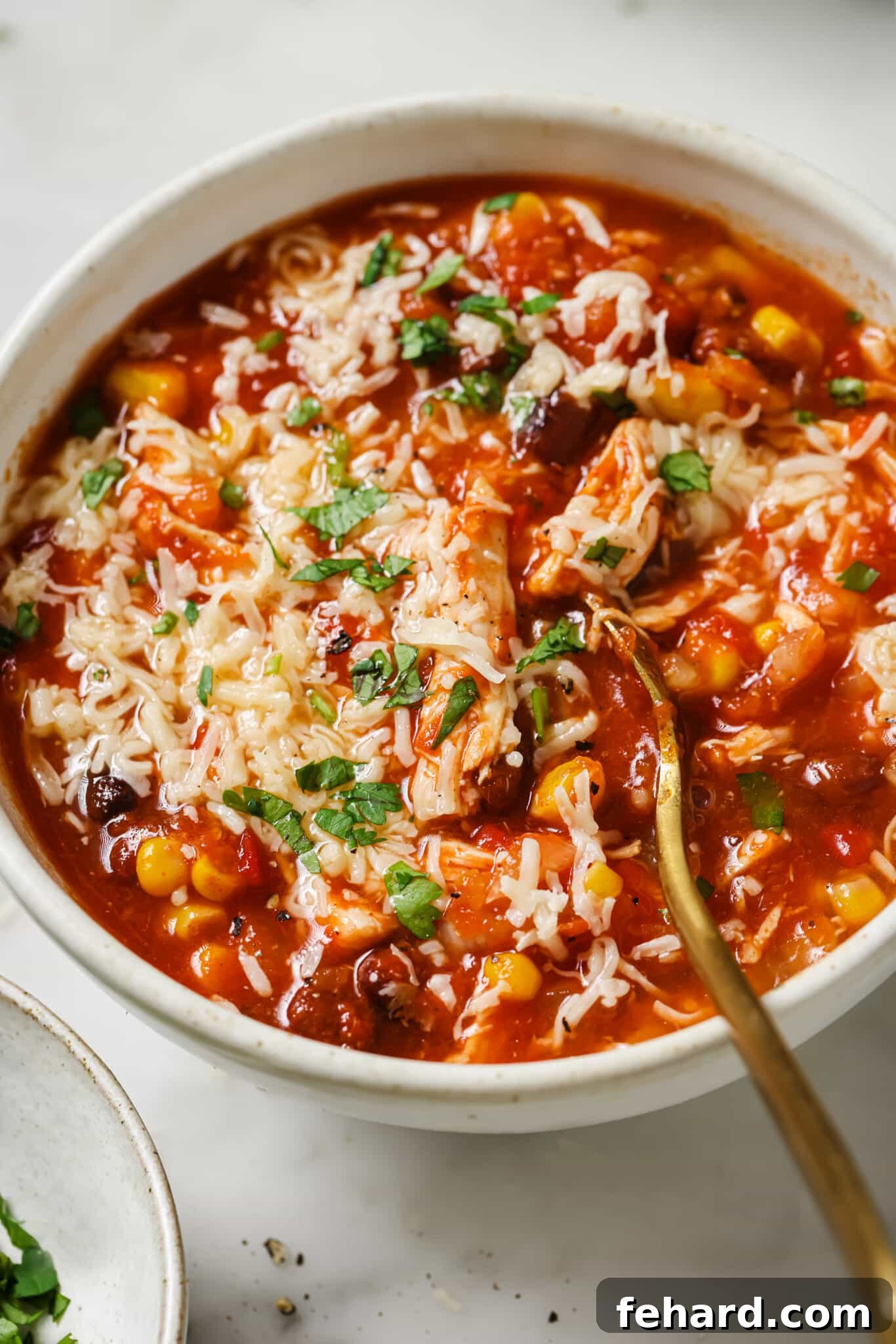 Close up of slow cooker chicken chili topped with cilantro and cheese.