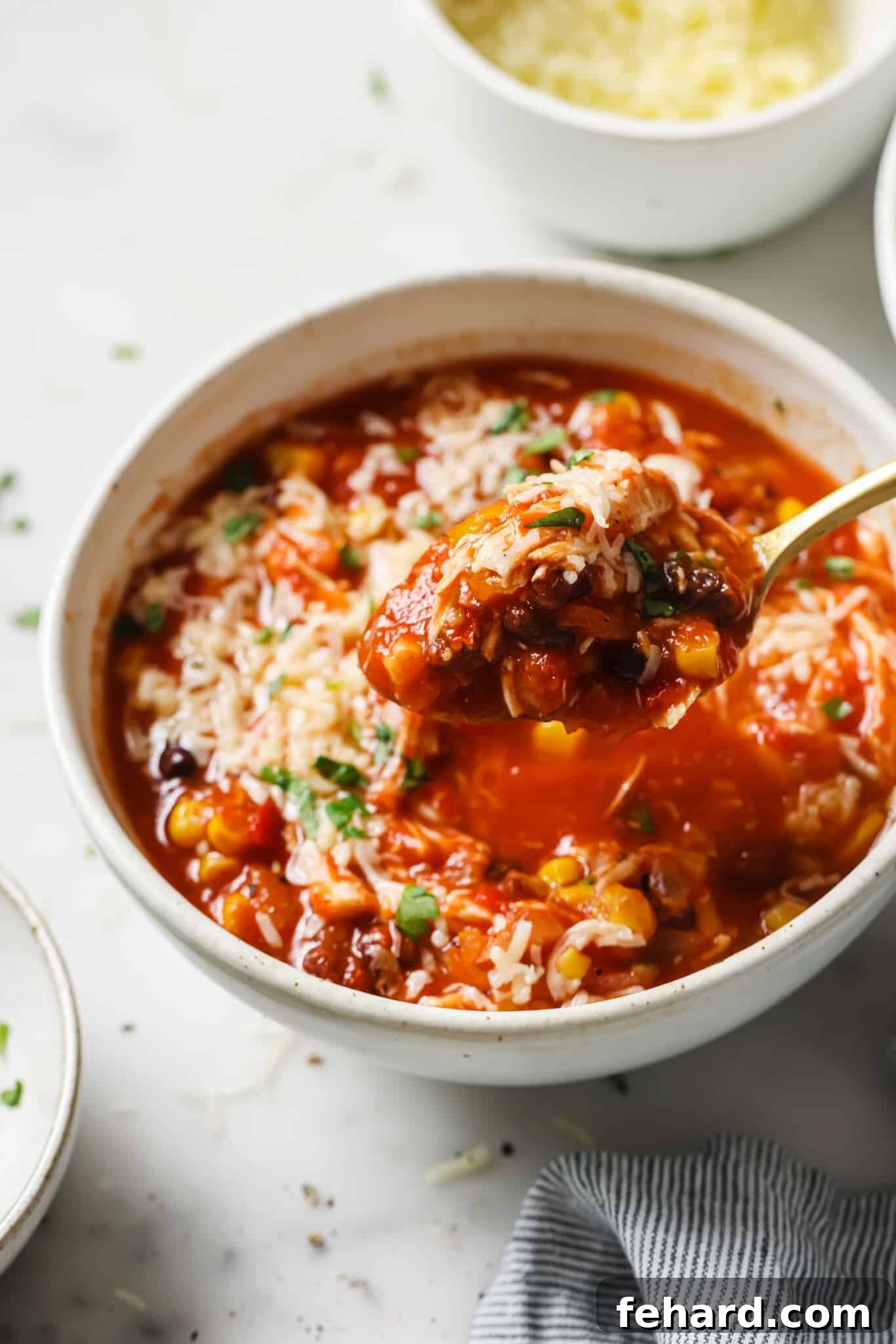 A bowl of slow cooker chicken chili with a spoon.