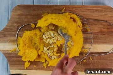 Whip Up Your Own Homemade Pumpkin Puree 7 Cooked pie pumpkin on cutting board scooping out seeds.
