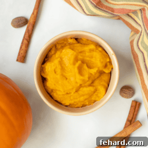 Homemade Pumpkin Puree in Bowl next to sugar pie pumpkin and cinnamon sticks.