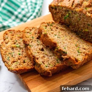 Close up of a moist slice of pineapple zucchini bread on a wooden cutting board, garnished lightly.