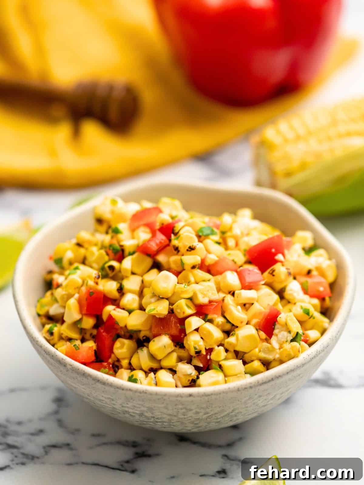 Grilled Corn Salsa Recipe Bowl of vibrant grilled corn salsa, garnished with fresh cilantro and a lime wedge, ready to be served.