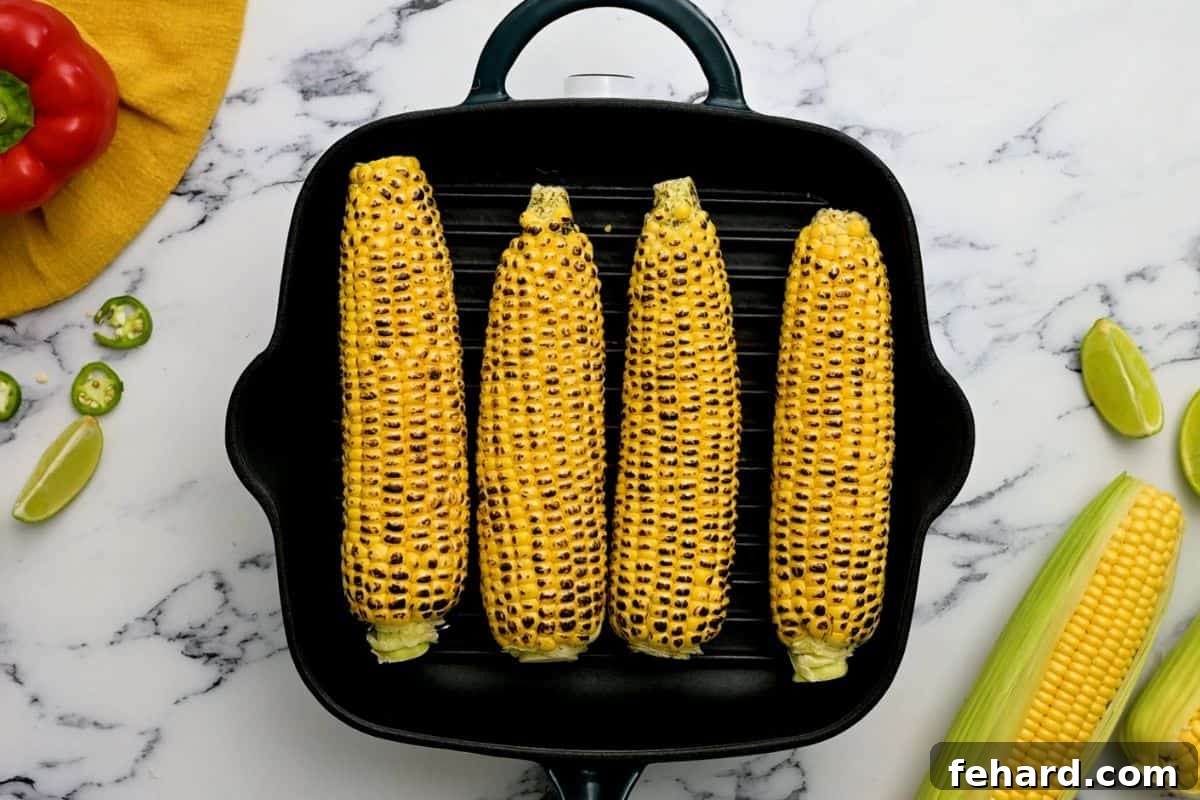 Grilling Corn for Salsa Fresh corn on the cob charring on a hot grill plate, showing early signs of browning.