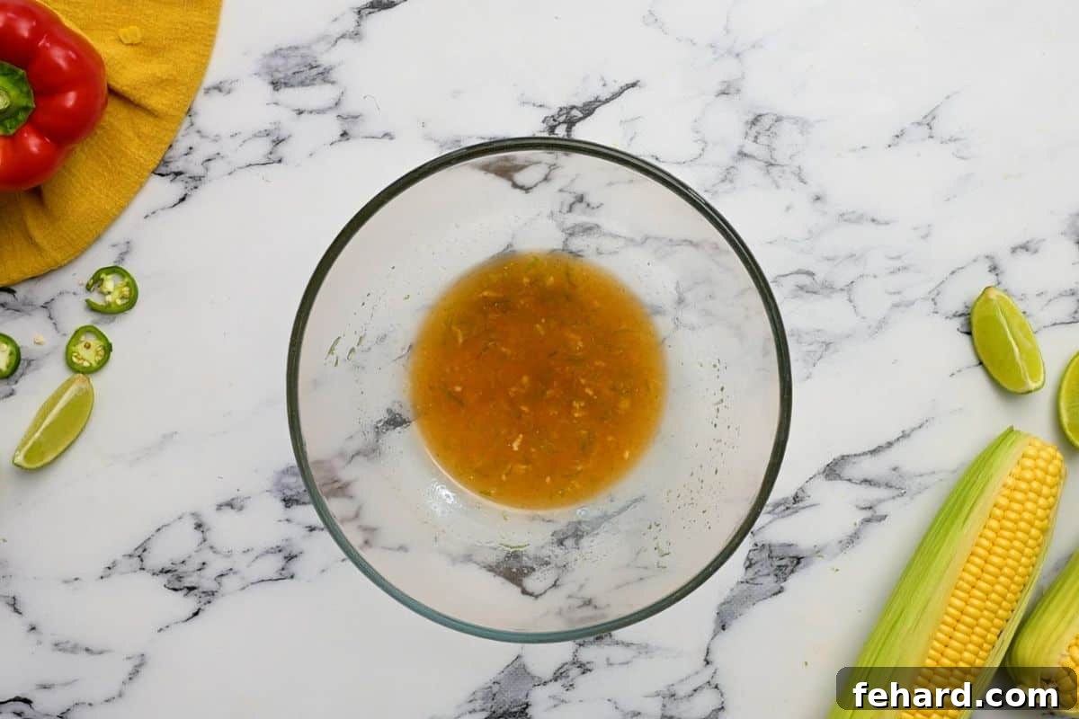 Honey Lime Dressing for Corn Salsa Clear glass bowl containing the whisked honey-lime dressing, showcasing its vibrant color and smooth texture.
