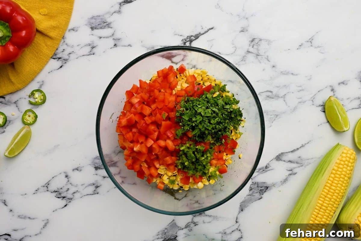 Mixing Corn Salsa Ingredients A vibrant mix of corn, bell peppers, cilantro, and jalapeño, coated in lime zest and dressing, ready for chilling.