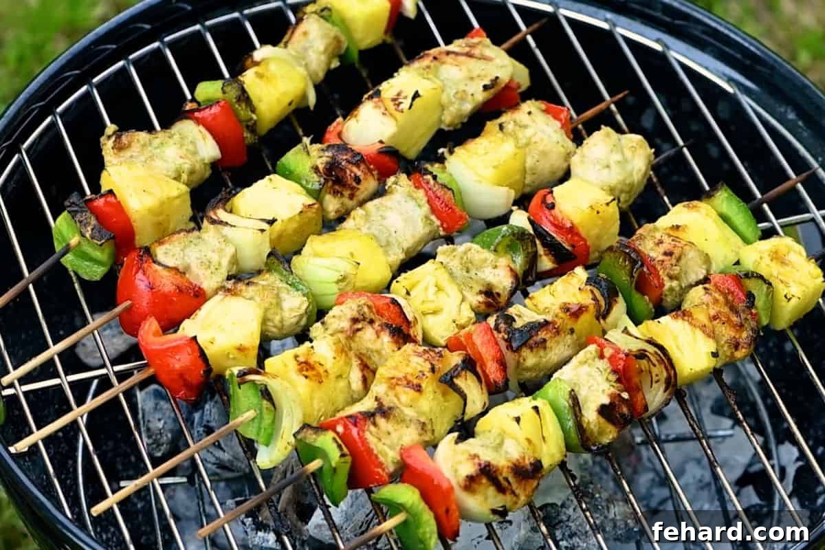 Spicy Grilled Jerk Chicken Skewers 8 Pineapple chicken kabobs sizzling on a charcoal grill, showing grill marks.