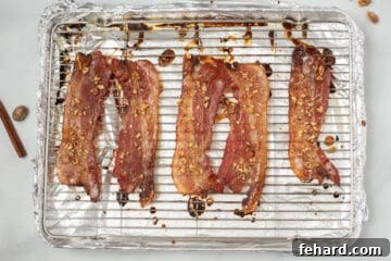 Oven-baked Candied Maple Bacon, perfectly browned and caramelized, fresh out of the oven on a baking sheet.