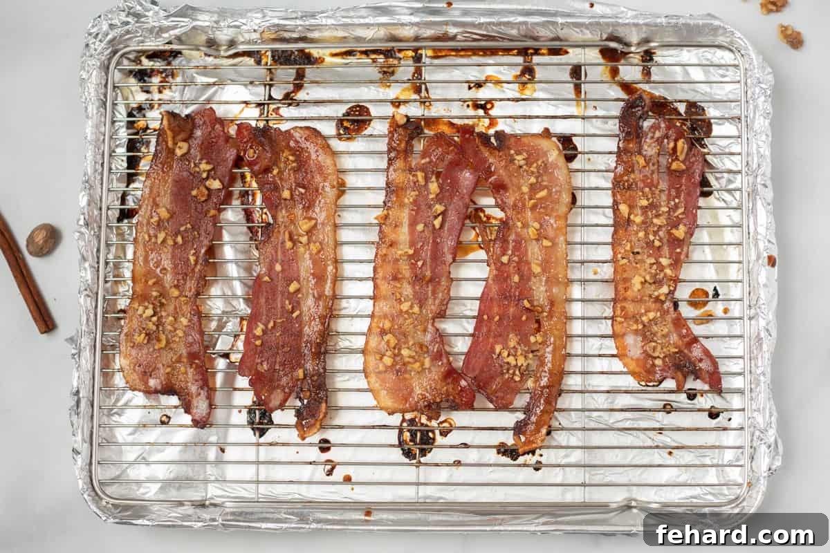 Perfectly cooked Candied Maple Bacon, golden-brown and crispy, arranged on a baking sheet pan fresh out of the oven, highlighting its irresistible glaze.