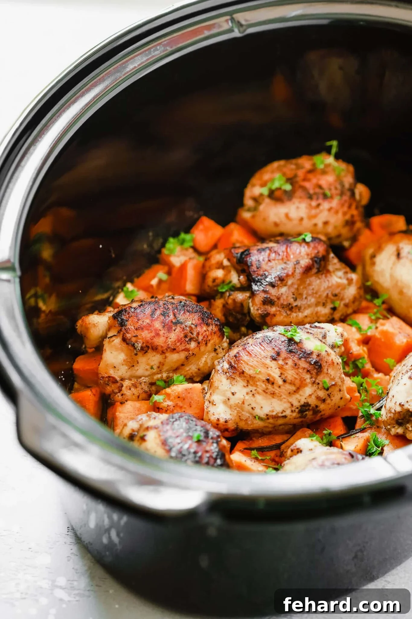 raw chicken thighs and sweet potato in a crockpot, ready for cooking