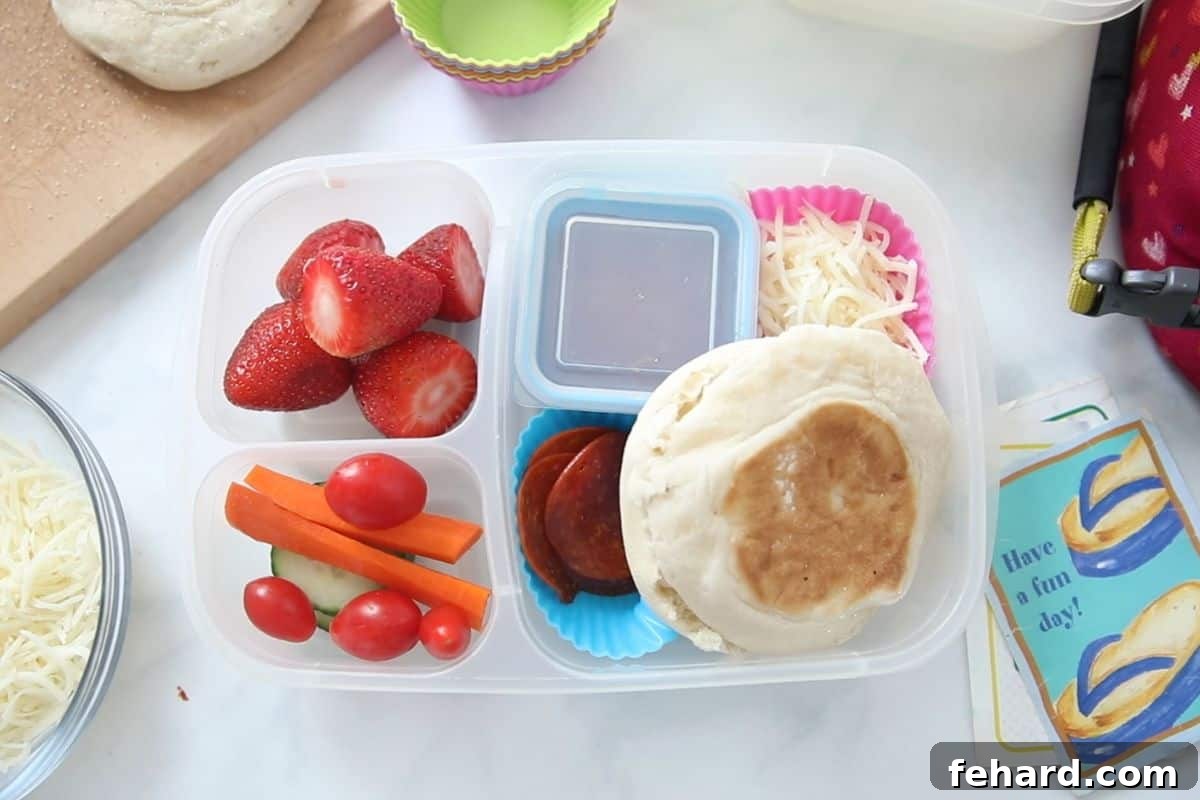 Pizza Lunchable with pepperoni, cheese, strawberries and veggies next to cute lunch note next to lunchbox.