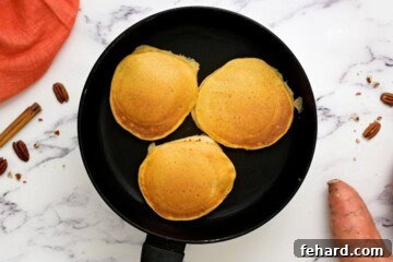 Fluffy sweet potato pancakes on skillet after cooking.