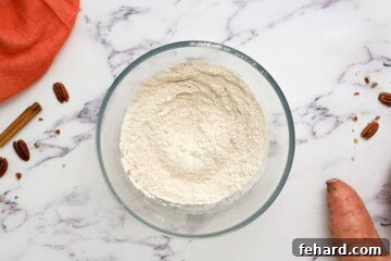 Sifted flour, baking powder, and warming spices in large mixing bowl for sweet potato pancake recipe.
