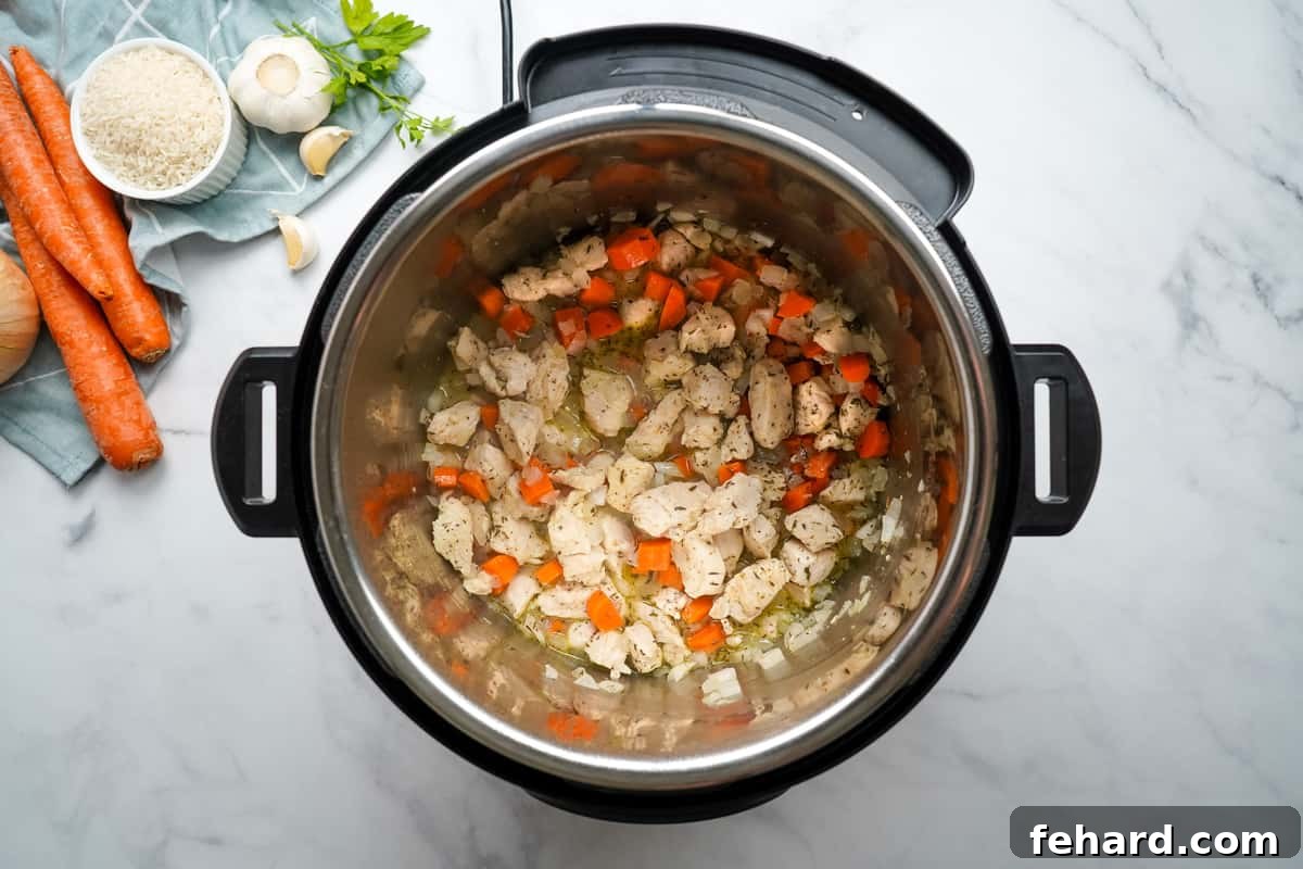 Instant Pot Chicken and Rice Casserole Sautéed chicken, carrots, and onions in the Instant Pot inner pot, being deglazed with white wine, creating a rich broth base.