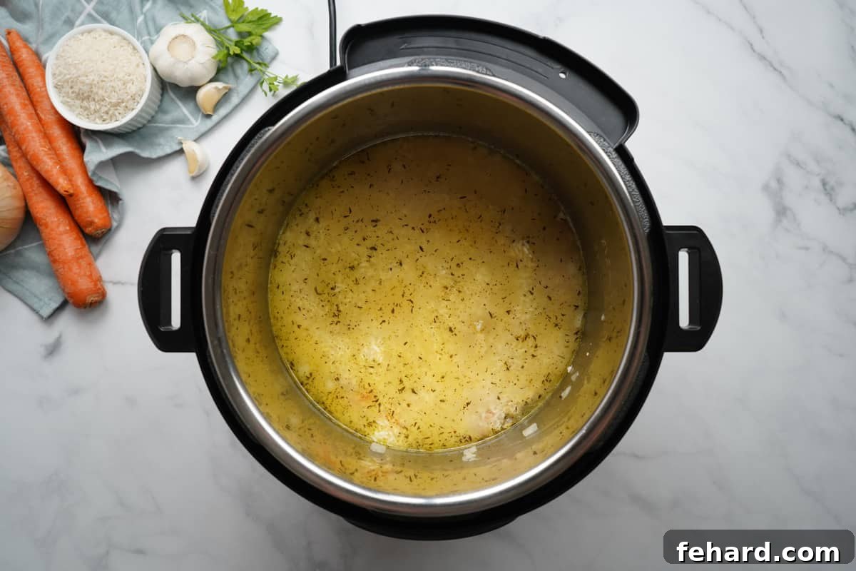 Chicken and Rice Recipe Pressure Cooker Instant Pot inner pot containing sautéed chicken, carrots, and onions, with chicken broth added, ready for the rinsed rice.