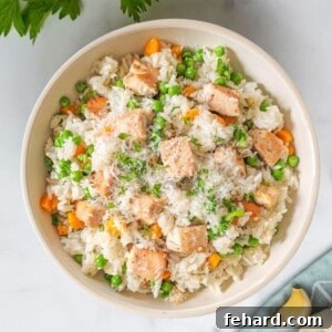 Bowl of Instant Pot Chicken and rice plated in cream bowl with garlic cloves in the background.
