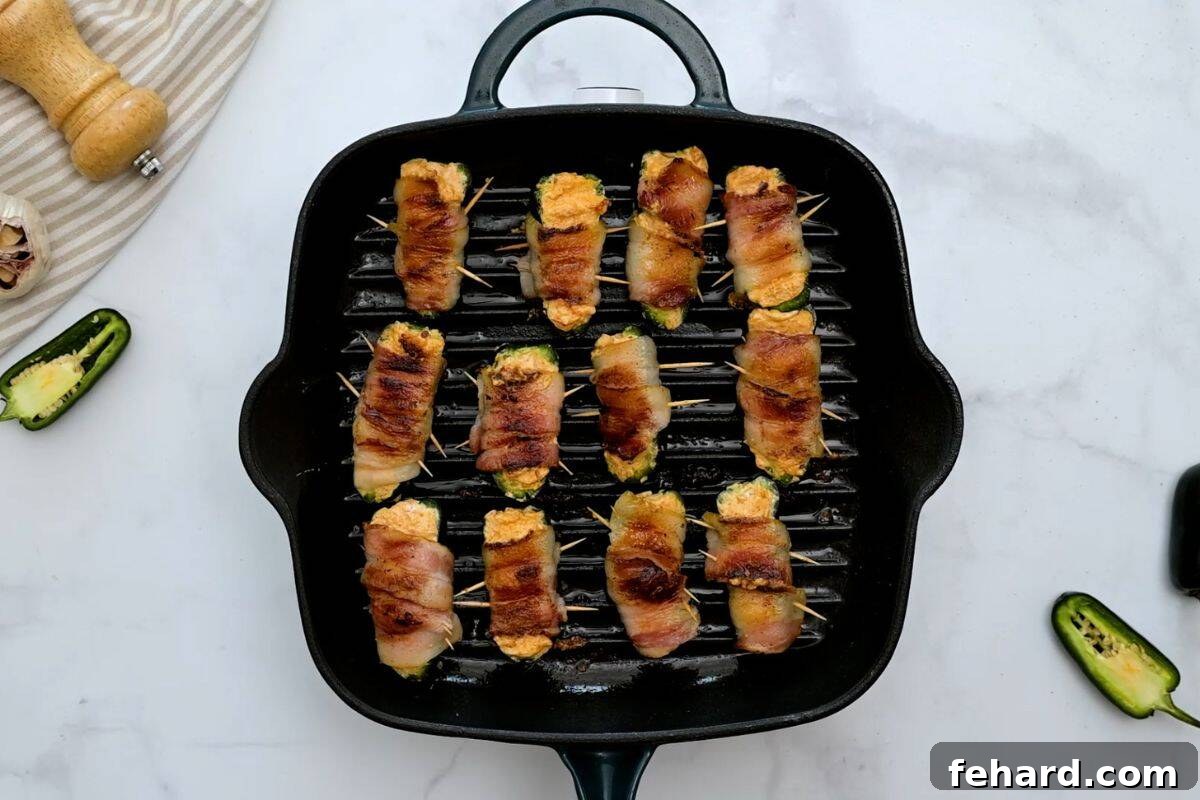 Jalapeno Poppers wtih Bacon Jalapeno poppers wrapped in bacon on small grill pan.