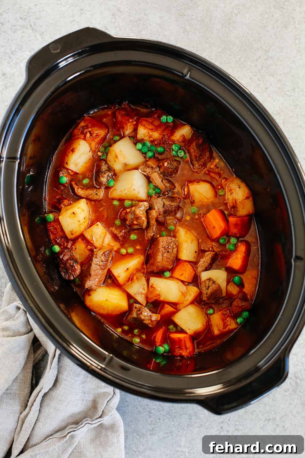 Healthy slow cooker beef stew inside of a black slow cooker. 