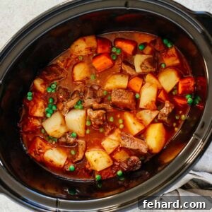 Healthy slow cooker beef stew inside of a black slow cooker.