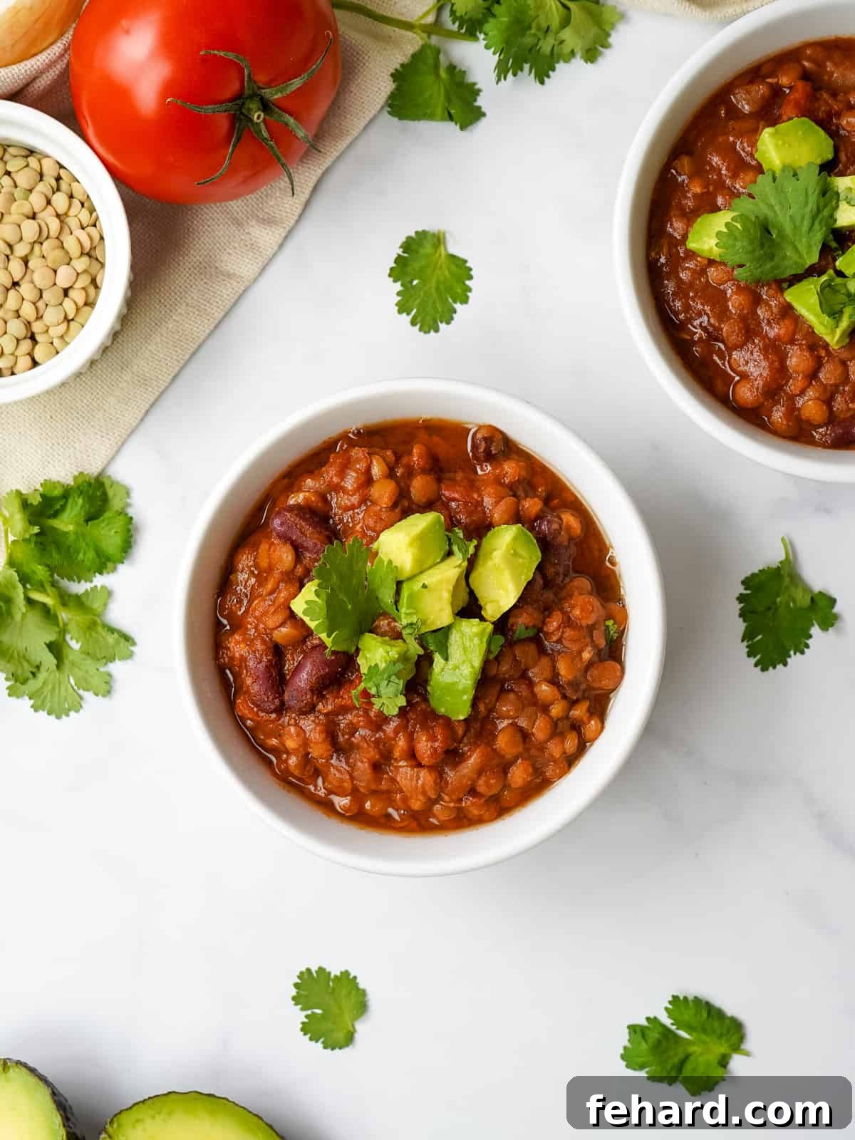 A steaming bowl of homemade Instant Pot Lentil Chili, generously topped with creamy avocado slices and fresh cilantro.