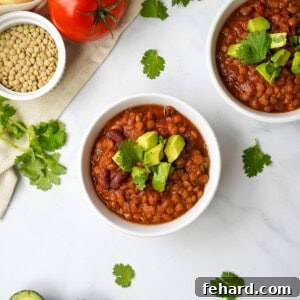 Instant Pot Lentil Chili in white bowl topped with diced avocado and cilantro.