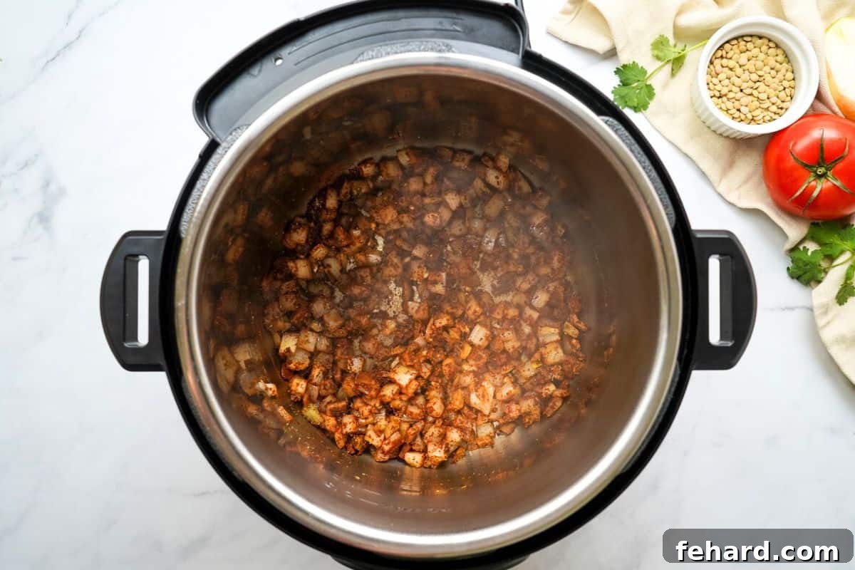 Minced onions and aromatic spices being toasted in the inner pot of an Instant Pot.