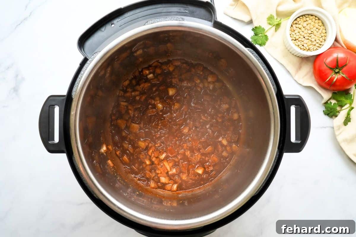 The inner pot of the Instant Pot after deglazing with red wine, showing sautéed onions and spices.