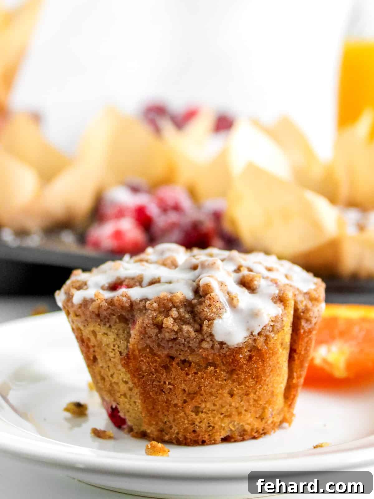 Cranberry Orange Muffins Recipe Baked Cranberry Orange Muffins on a white plate next to fresh orange slices, ready to be enjoyed.